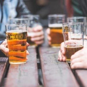 Personas disfrutando de cerveza en un lugar al aire libre indicando quienes son los consumidores que toman más cerveza