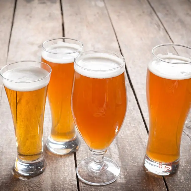 Cinco vasos con en diferentes estilos de cerveza sobre una mesa de madera ilustrando por qué es mejor beber cerveza en vaso