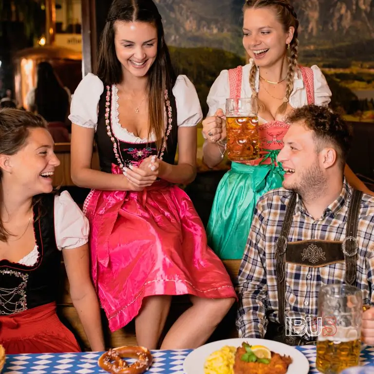 Grupo de amigos con vestimenta típica del Oktoberfest: Dirndl y Lederhosen, disfrutando cervezas y comida tradicional.