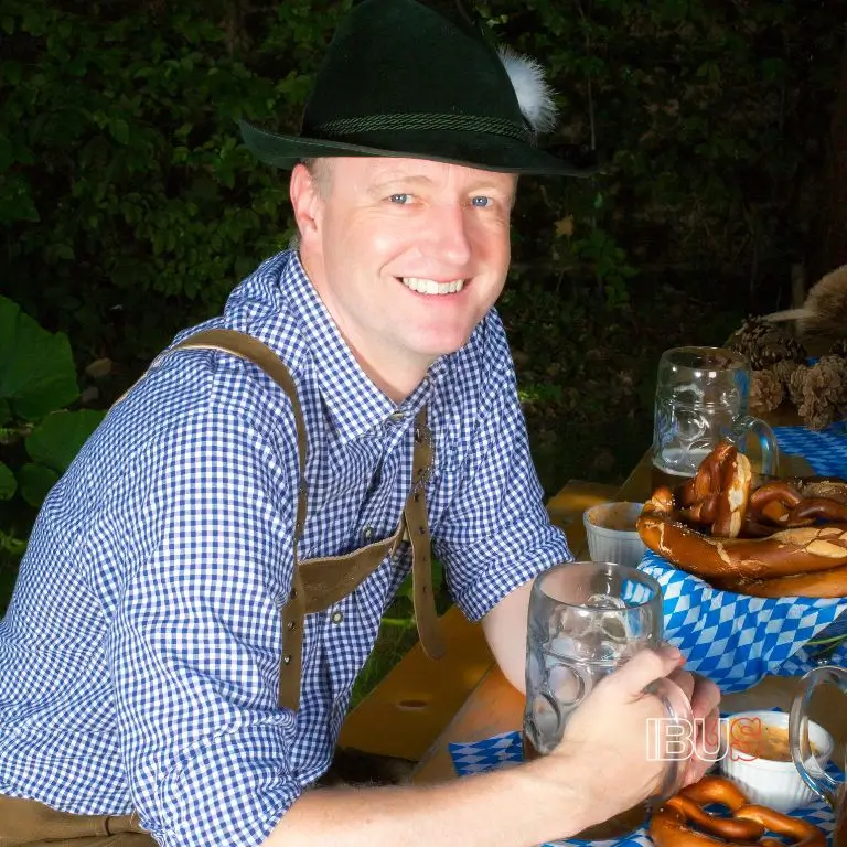 Hombre vistiendo Lederhosen, el atuendo tradicional del Oktoberfest, con sombrero bávaro y camisa de cuadros.