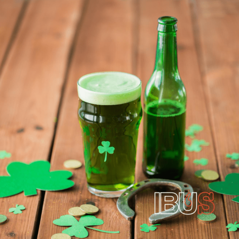 Cerveza de color verde en vaso cervecero y una botella verde con tréboles de papel y herradura