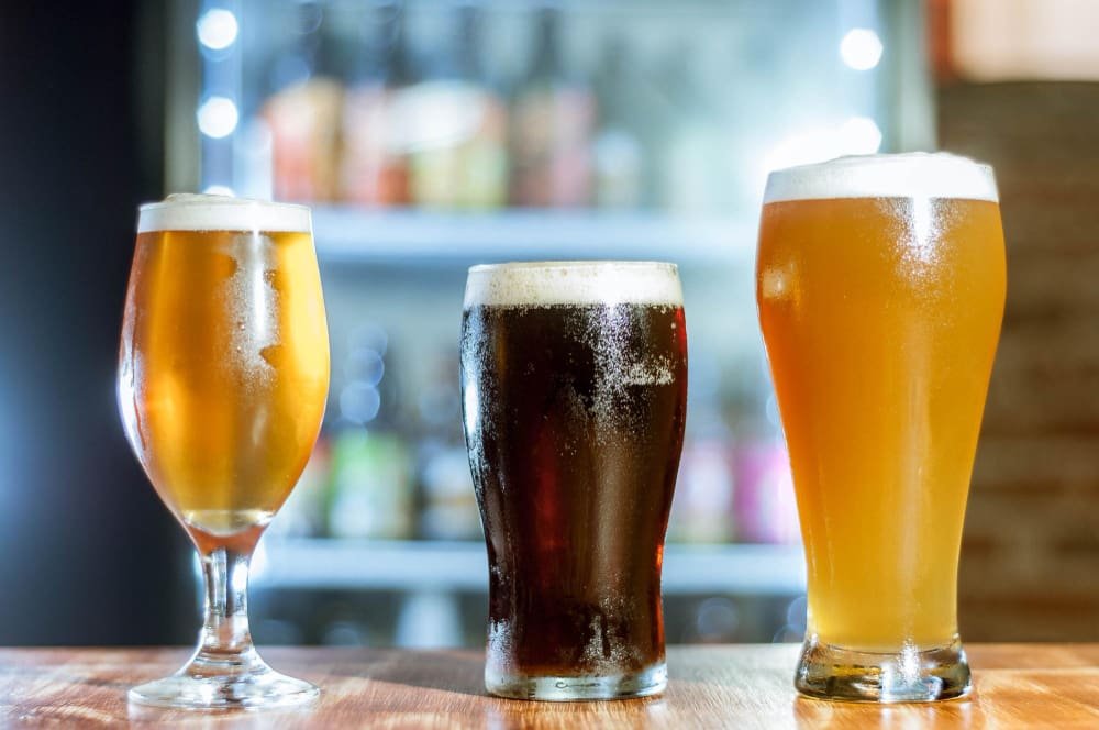 Tres vasos de cerveza con diferentes estilos, representando la clasificación de los estilos de cerveza.